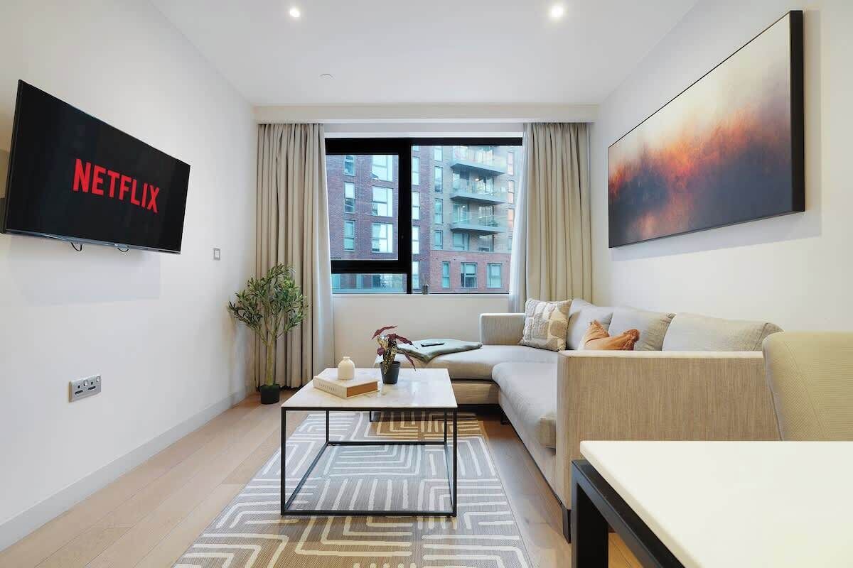 Ein modernes Wohnzimmer mit einer Couch, einem Couchtisch und einem Fernseher, der das Netflix-Logo zeigt.