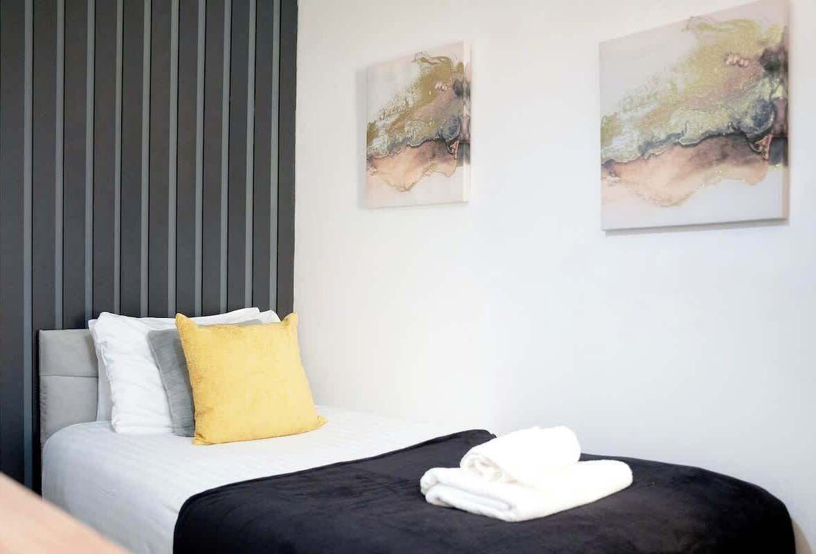 Habitació d'hotel moderna amb llit, almoinos i obra d'art abstracta a la paret.