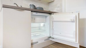 A kitchen with a built-in refrigerator, a microwave, and a kettle on the countertop. - Chic Middlesbrough Studio|Sleeps 2|By Stay with us (Middlesbrough)