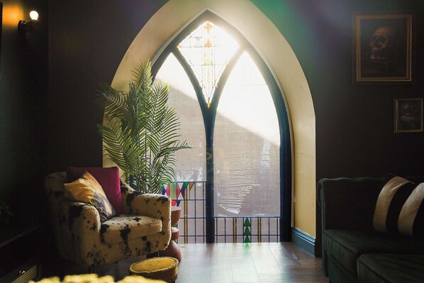 A cozy room with a large arched window, a potted plant, and two sofas.