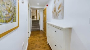 A hallway with wooden flooring, white walls, a staircase, and a white dresser with drawers. - Charming 3-Bedroom Home in the Heart of Stanhope (Stanhope)