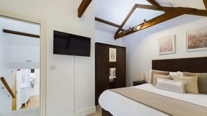 A bedroom with a bed, a flat-screen TV, a dark headboard, and artwork on the wall. - Charming 3-Bedroom Home in the Heart of Stanhope (Stanhope)