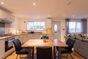 A modern kitchen with a dining table, chairs, and a sofa in a living area.