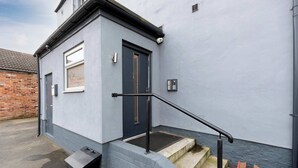 A building with a dark blue door, a small window, and a black handrail leading to a set of steps. - Middlesborough City Centre Studio (Middlesbrough)