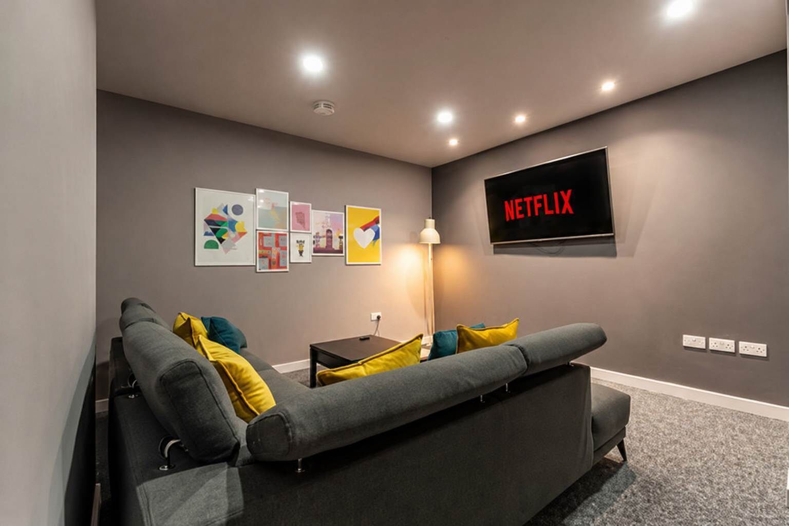 A modern living room with a gray sofa, a flat-screen TV, and wall art.