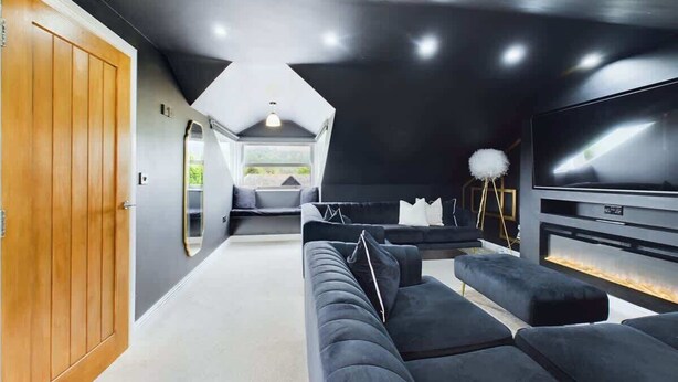 A modern interior with a sectional sofa, a flat-screen TV, and a ceiling with a skylight. - Modern 4 Bed, Walk to Pubs, Shops and Countryside (Stanhope)