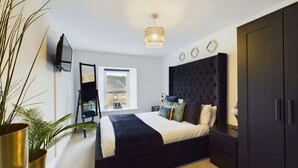 A modern bedroom with a large bed, dark wardrobe, and a small window. - Modern 4 Bed, Walk to Pubs, Shops and Countryside (Stanhope)