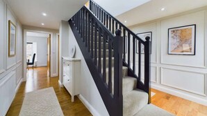 A staircase with a dark handrail and a carpeted landing. - Modern 4 Bed, Walk to Pubs, Shops and Countryside (Stanhope)