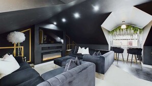 A modern living room with a fireplace, dark sofas, and a TV. - Modern 4 Bed, Walk to Pubs, Shops and Countryside (Stanhope)