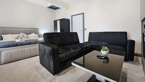 Una sala de estar moderna con un sofá, una mesa de centro y una cama con cabecera.