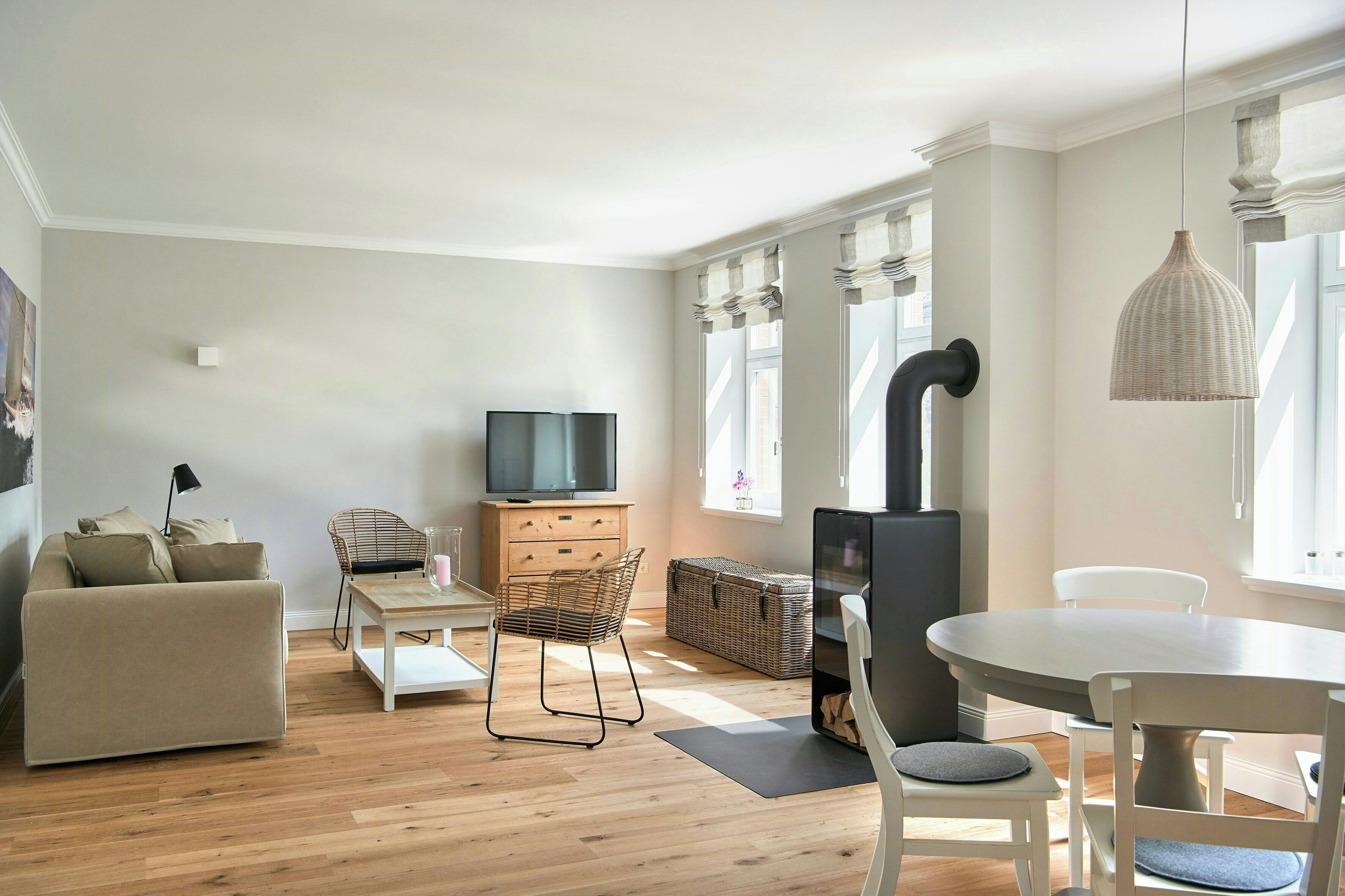 Ein modernes Wohnzimmer mit einer Couch, einem Fernseher, einem Esstisch, Stühlen und einem Kamin.