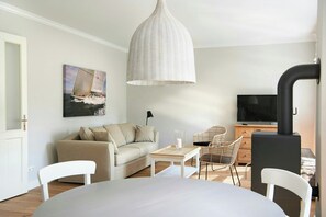 Ein Wohnzimmer mit einer Couch, Sesseln, einem Tisch, einem Fernseher und einem Kamin.