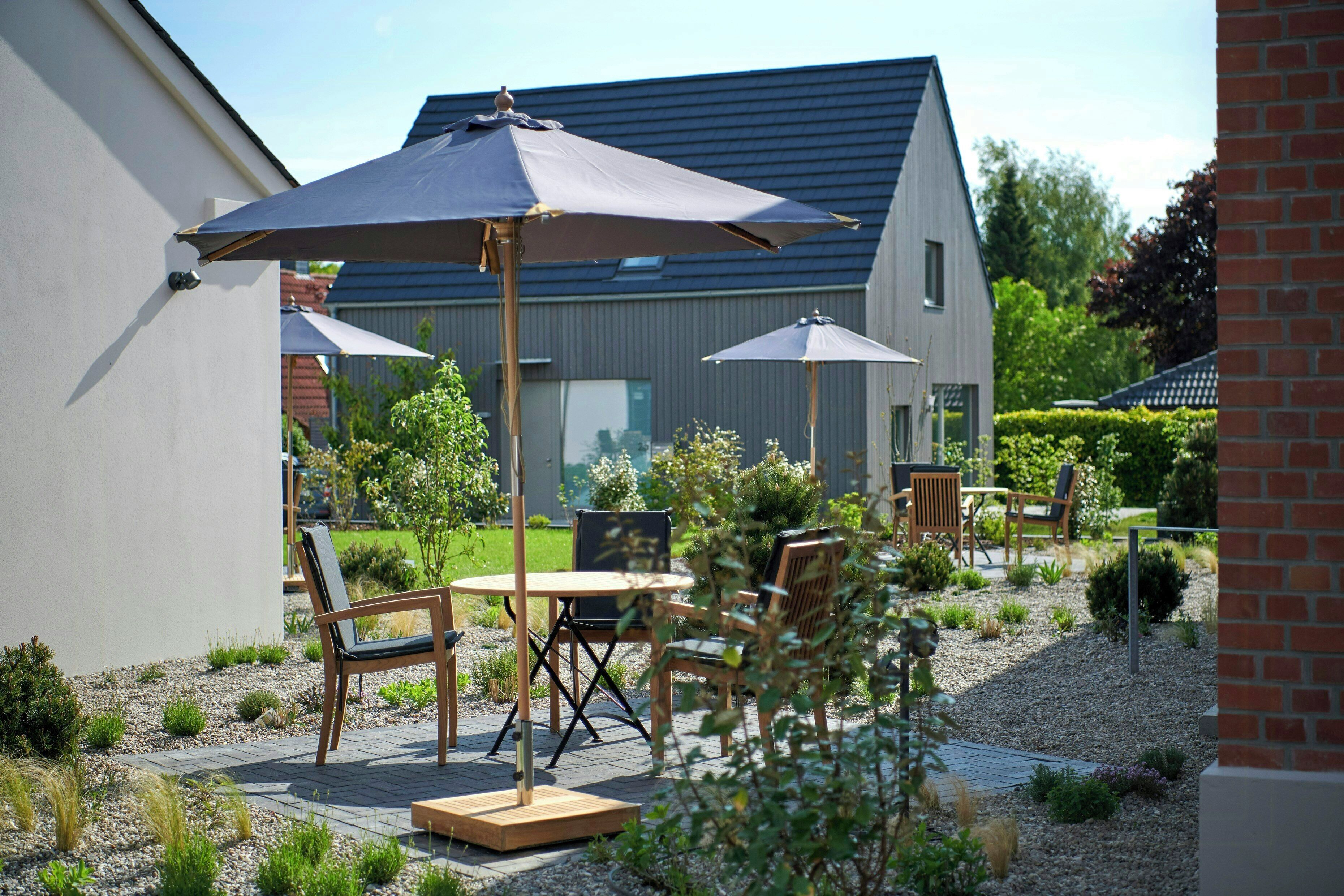 A patio with outdoor furniture, a table, and two umbrellas.