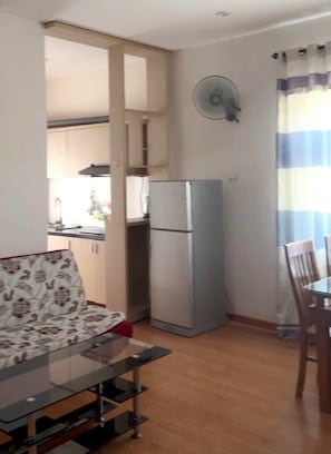 A compact living space with a kitchenette, a dining area with a glass table, and a refrigerator. - SeaFa Hotel & Apartment (Da Nang)