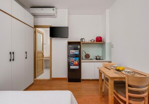 A compact hotel room with a bed, a kitchenette, a dining area, and a TV mounted on the wall. - SeaFa Hotel & Apartment (Da Nang)