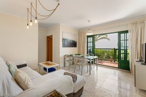 Ein modernes Wohnzimmer mit einer Couch, einem Esstisch und Blick auf einen Balkon.