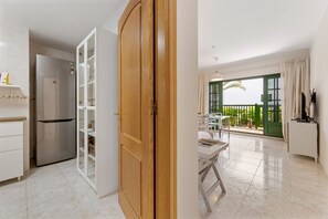 Eine Küche mit Kühlschrank, einer Holztür und einem Essbereich mit Tisch und Stühlen.