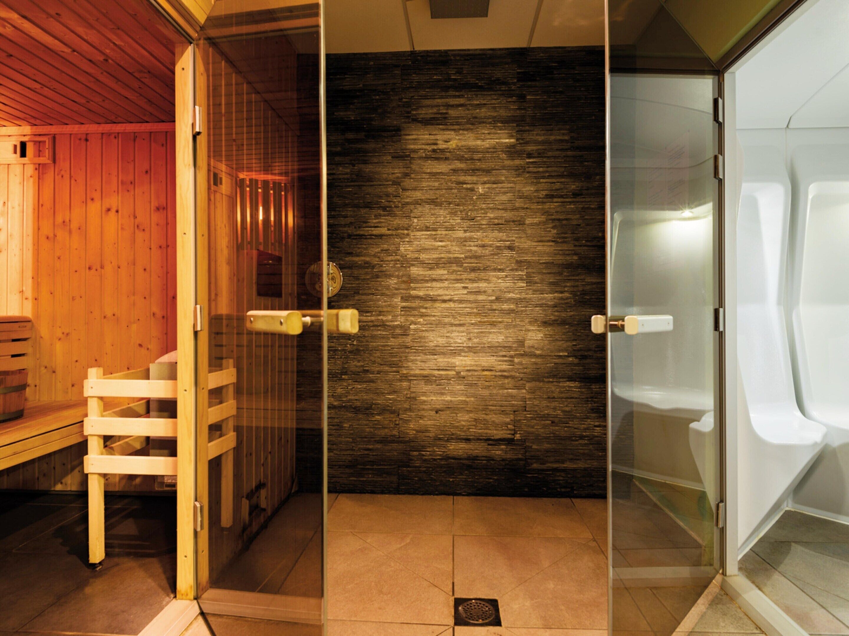 Una sala de sauna con paredes de madera, una puerta de cristal y un banco.