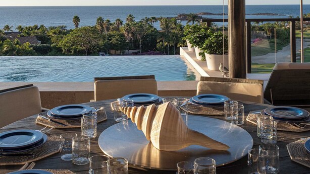 A dining table set with plates, glasses, and cutlery, overlooking a pool and ocean view. - PH Azure: 4BR Oceanview Penthouse w/ Private Heated Infinity Pool & Rooftop (Punta Mita)