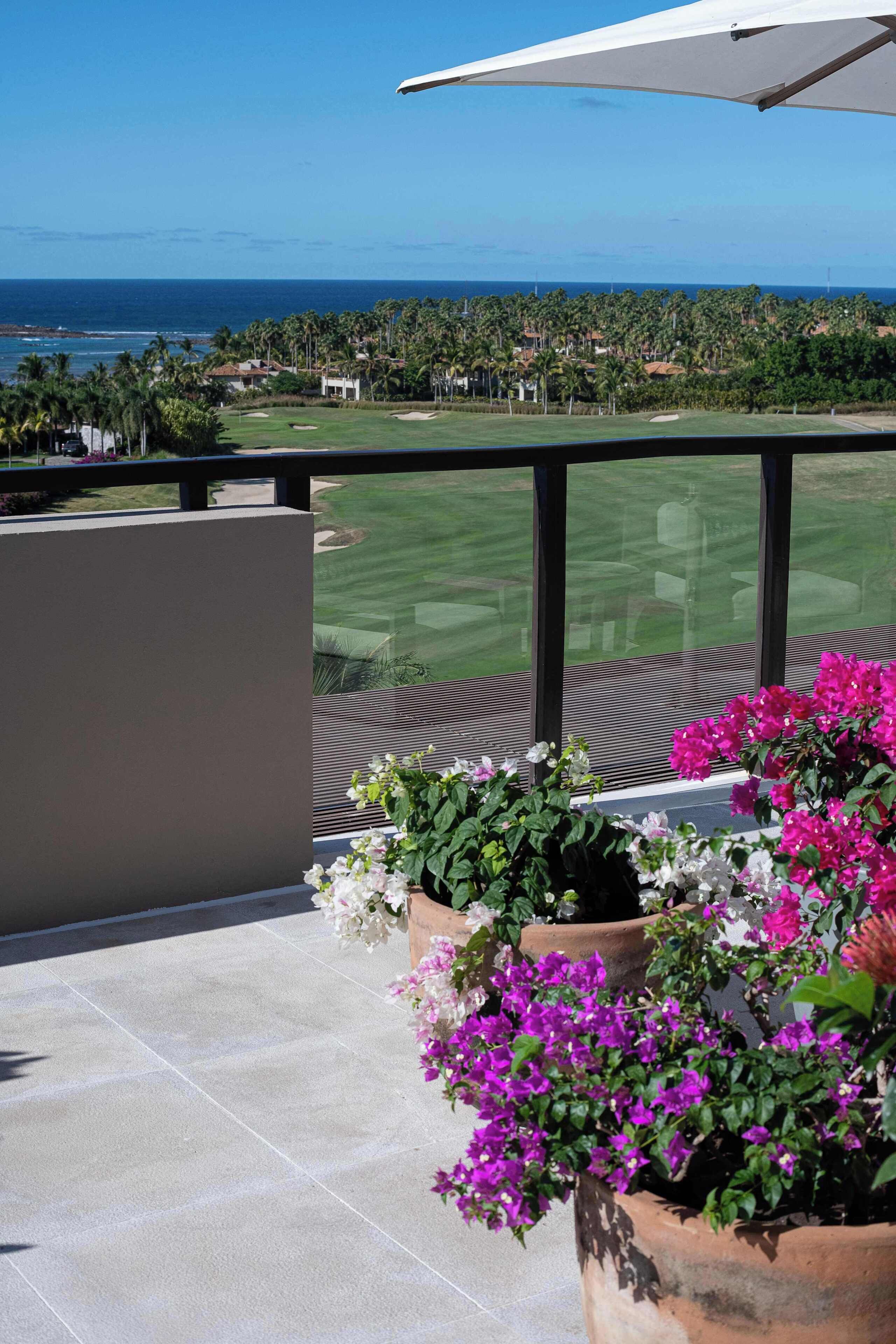 Ein Balkon mit Blick auf einen Golfplatz und den Ozean.