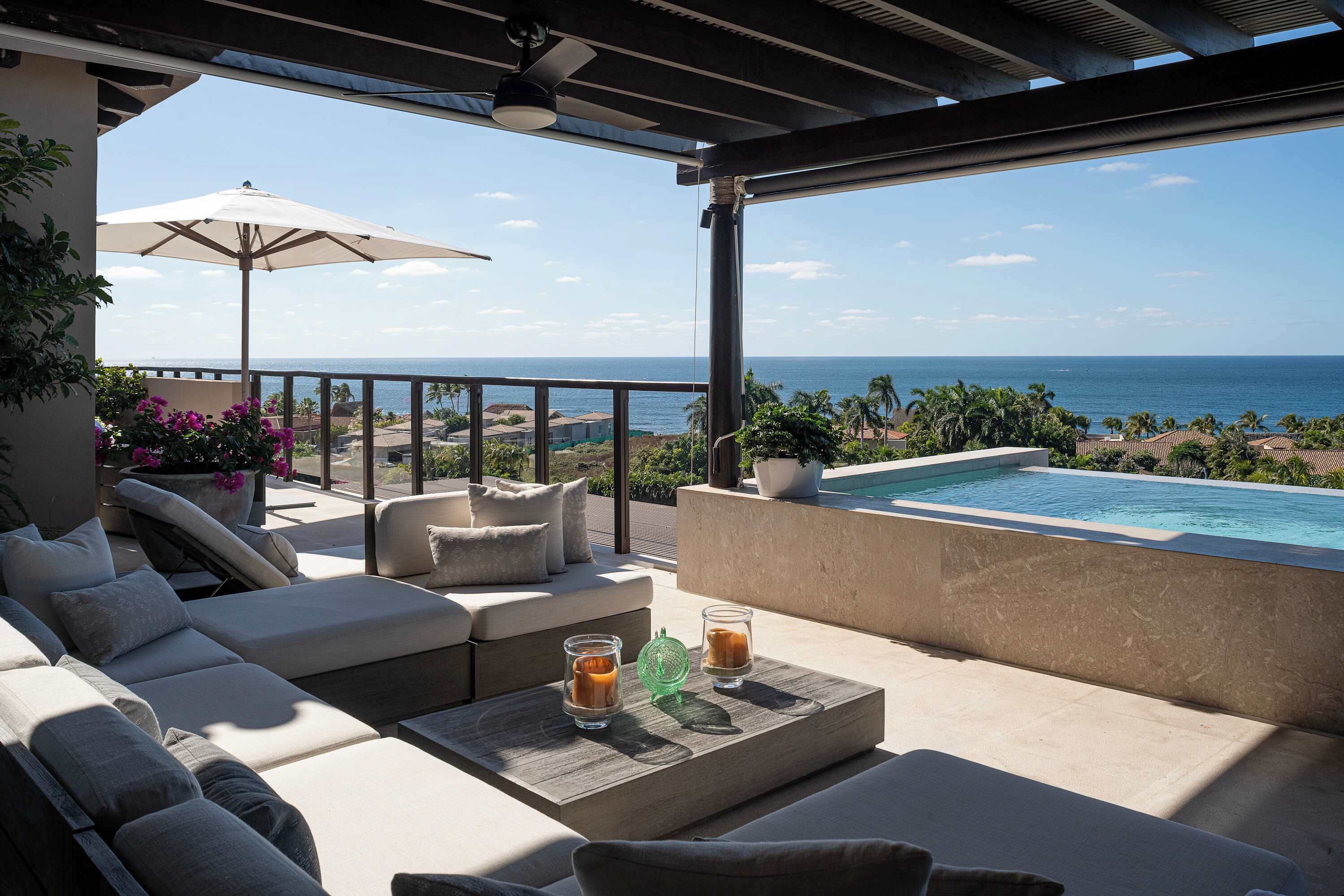 En balkon med pool, udendørs møbler og havudsigt.