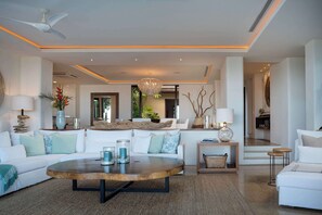 Ein modernes Wohnzimmer mit rundem Couchtisch, weißen Sofas und einer Chandelier.
