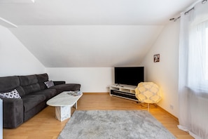 A modern living room with a sofa, a coffee table, a TV, and a lamp. - Apartment 'House Ana' with Shared Terrace, Balcony and Wi-Fi (Aach)