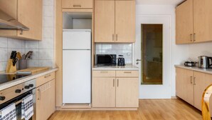 A compact kitchen with wooden cabinets, a microwave, a coffee maker, and a refrigerator.