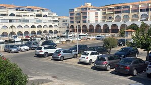 A marina with parked cars and boats, surrounded by multi-story buildings with arched windows and a tiled roof. - Charming and cosy T2 near the beach, parking space (Sète)