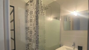 A bathroom with a shower, a sink, and a mirror. - Charming and cosy T2 near the beach, parking space (Sète)