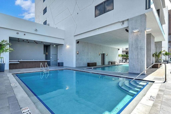 Ein moderner Poolbereich im Innenbereich mit klaren Poolrändern, einer Bar und einer Treppe, die auf eine erhöhte Ebene führt.