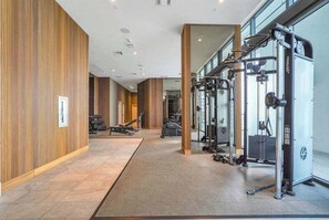 Ein modernes Fitnessstudio mit Trainingsgeräten, Holzwänden und einem gefliesten Boden.