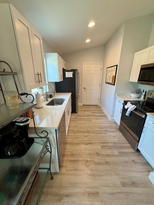 A modern kitchen with white cabinetry, a stainless steel refrigerator, a microwave, and a coffee maker. - Guest Favorite , Pet-Friendly Retreat Near Top Springs &
World Equestrian center (Ocala)