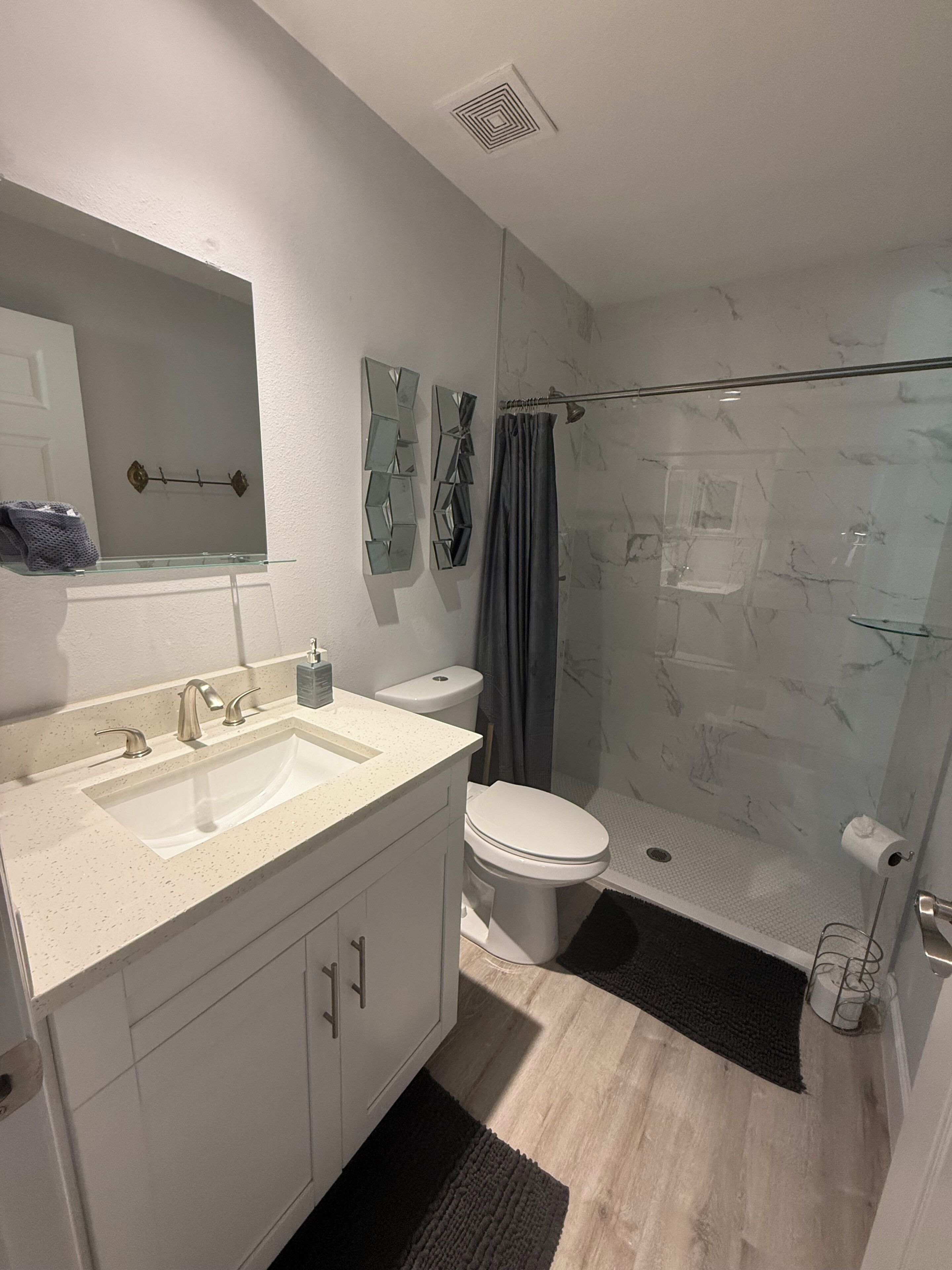 Une salle de bain moderne équipée d’un lavabo, de toilettes et d’une douche.