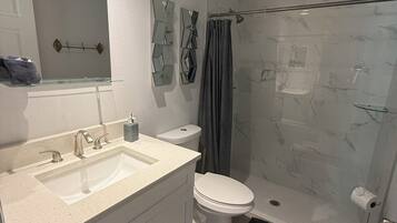 Une salle de bain moderne équipée d’un lavabo, de toilettes et d’une douche.