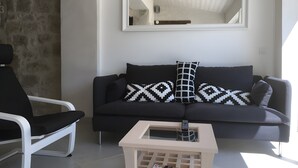 En moderne stue med en sort sofa, en hvid lænestol og et lille hvidt sofabord.