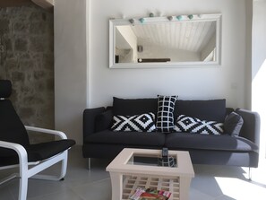 Ein modernes Wohnzimmer mit einer schwarzen Couch, einem weißen Sessel und einem kleinen weißen Couchtisch.