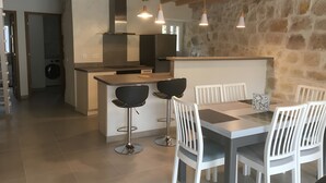 Et moderne køkken med en central ø, barstole og et spisebord med stole.