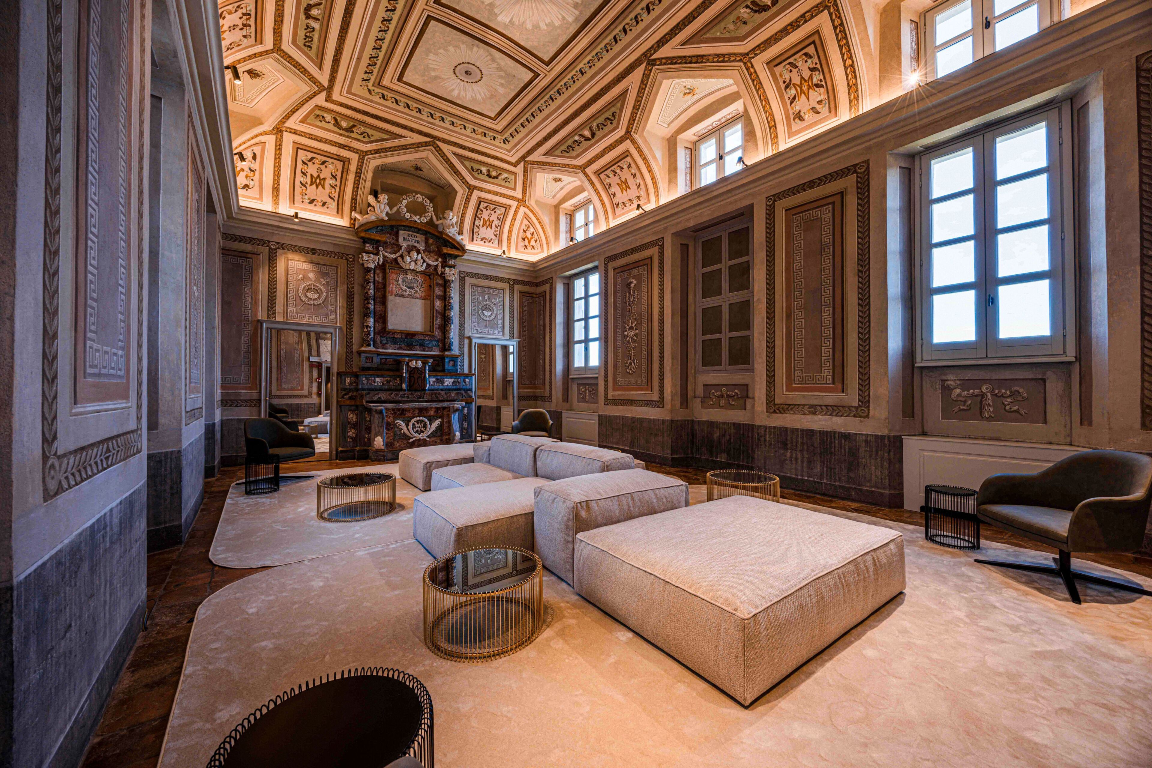 A luxurious room with a large sectional sofa, a fireplace, and ornate ceiling decorations.