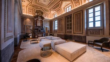 A luxurious room with a large sectional sofa, a fireplace, and ornate ceiling decorations.