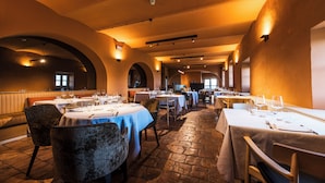 A restaurant with tables set for dining, featuring a stone floor and arched ceilings.