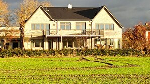A two-story house with a balcony, a garage, and a large front lawn. - Ruhe, Natur & Strandnahe auf Fehmarn (Fehmarn)
