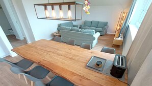 A modern kitchen with a wooden table, grey chairs, a toaster, and a hanging light fixture. - Ruhe, Natur & Strandnahe auf Fehmarn (Fehmarn)