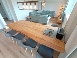 Una cocina moderna con una mesa de madera, sillas grises, un tostador y una lámpara colgante.