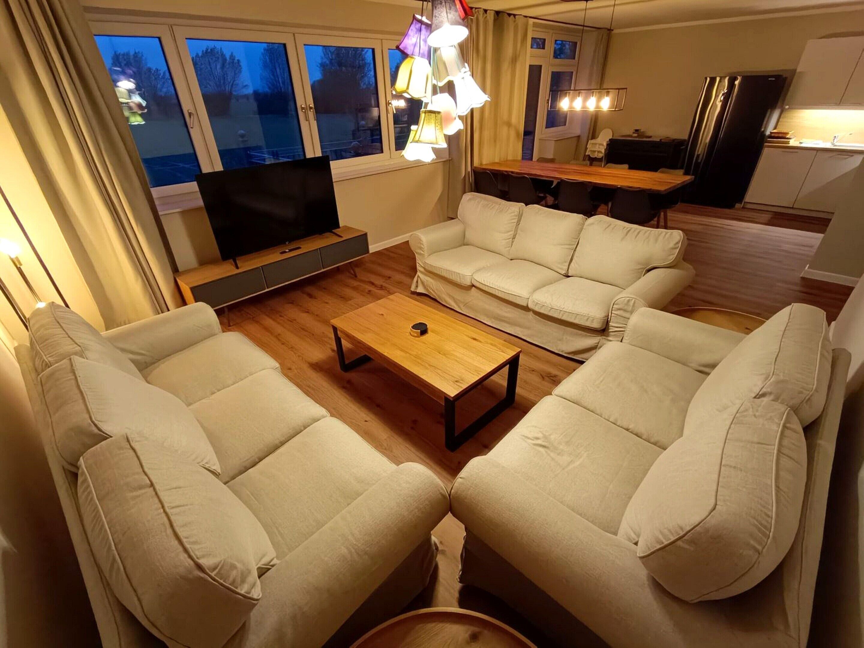 A living room with a sofa set, a coffee table, a TV, and a dining area with a table and chairs.
