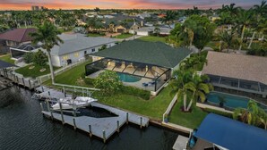 En bostadsfastighet med ett stort hus, en swimmingpool och en brygga med en båt.