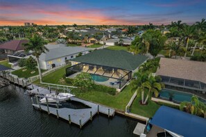 A residential property with a large house, a swimming pool, and a dock with a boat. - VRCC Villa Casa del Sol (Cape Coral)