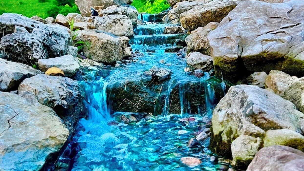 Uma nascente natural com pedras e água cristalina.