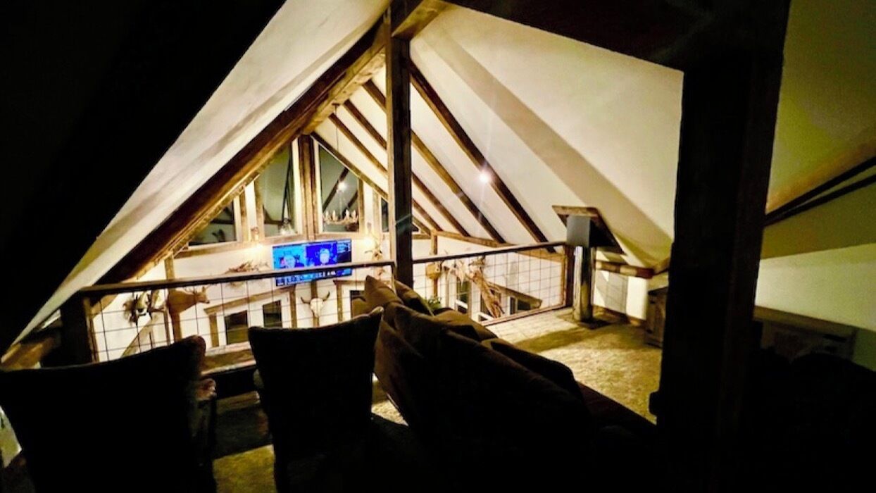 Ein Dachzimmer mit schrägem Dach, einem Fernseher und einem Fenster.