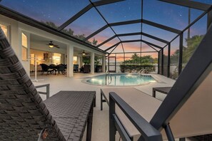 Ein überdachter Poolbereich mit Blick auf den Nachthimmel, eine Terrasse mit Sitzgelegenheiten und ein Essbereich.